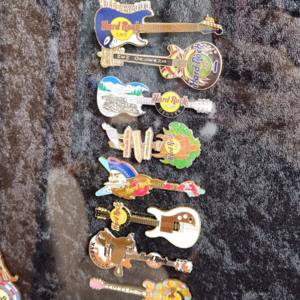 e148- large collection of Hard Rock Cafe pins arranged in the