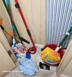 v113- contents of broom closet. Ironing board, cleaning tools